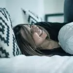 Спете с повдигнати крака на възглавница